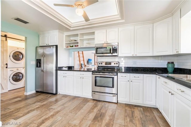 kitchen featuring stacked washer and clothes dryer, a raised ceiling, visible vents, a barn door, and appliances with stainless steel finishes