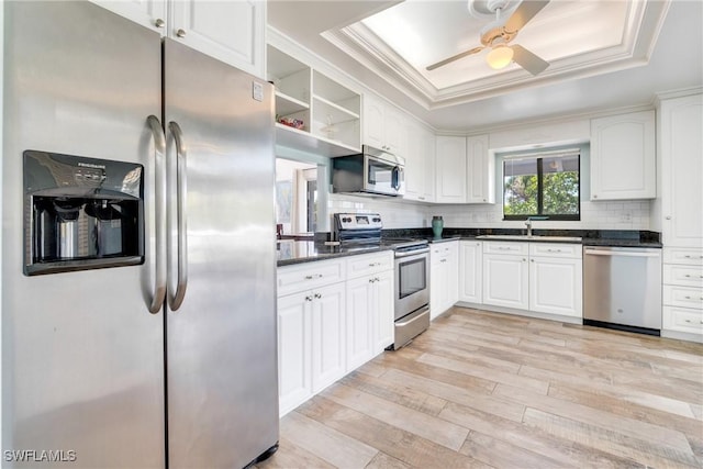 kitchen with dark countertops, stainless steel appliances, a sink, and a raised ceiling