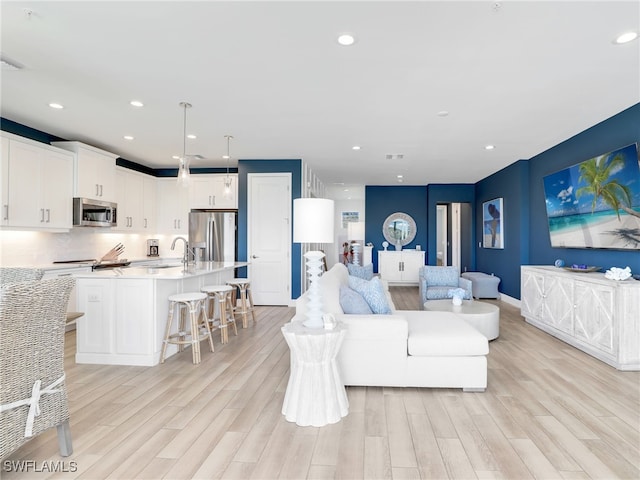 living room with light wood-style floors, baseboards, visible vents, and recessed lighting