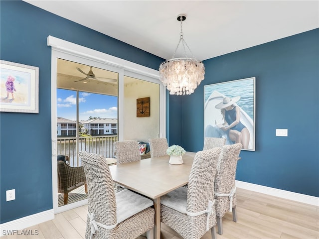 dining room with baseboards, wood finished floors, and ceiling fan with notable chandelier