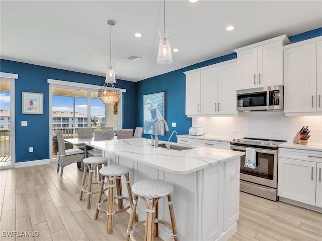 kitchen featuring white cabinets, appliances with stainless steel finishes, backsplash, and a sink