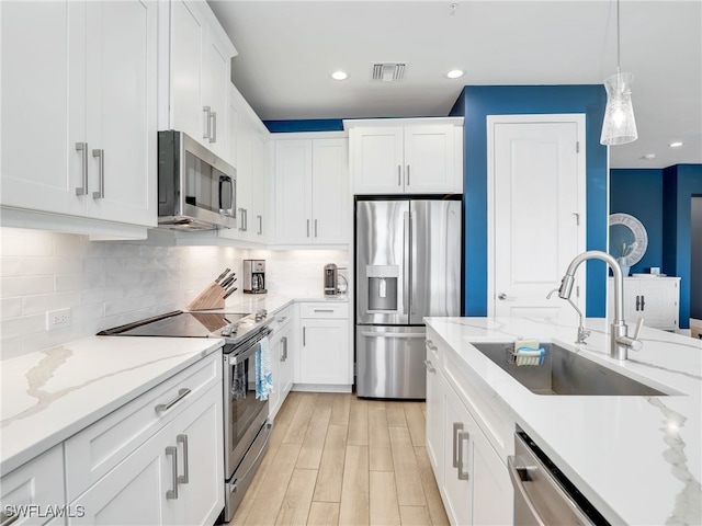 kitchen featuring stainless steel appliances, white cabinets, a sink, and backsplash