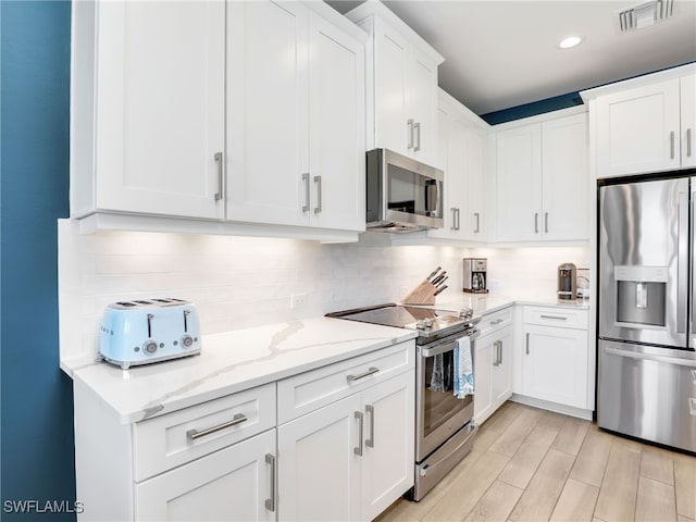 kitchen featuring visible vents, appliances with stainless steel finishes, white cabinets, and backsplash