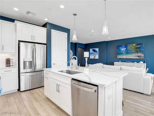 kitchen with stainless steel appliances, open floor plan, visible vents, and a sink