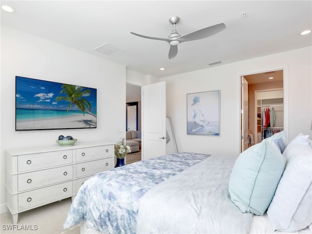 carpeted bedroom with a walk in closet, recessed lighting, visible vents, attic access, and ceiling fan