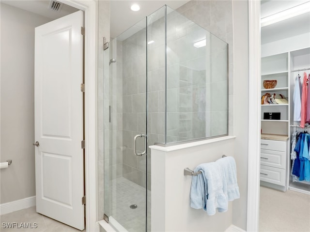 full bath with tile patterned flooring, visible vents, baseboards, a stall shower, and a walk in closet