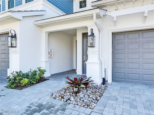 doorway to property with decorative driveway and stucco siding