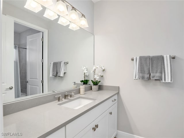 bathroom with a shower, vanity, and baseboards