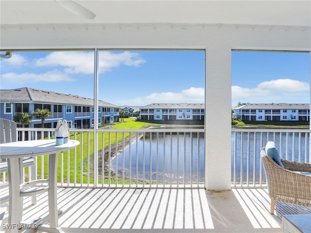 sunroom / solarium featuring a water view and a residential view