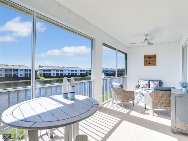 sunroom featuring a water view, a residential view, a wealth of natural light, and a ceiling fan