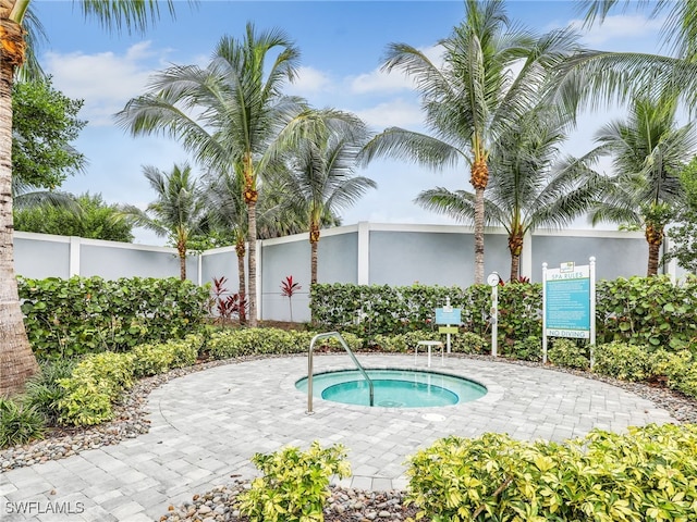 view of pool with a hot tub and fence