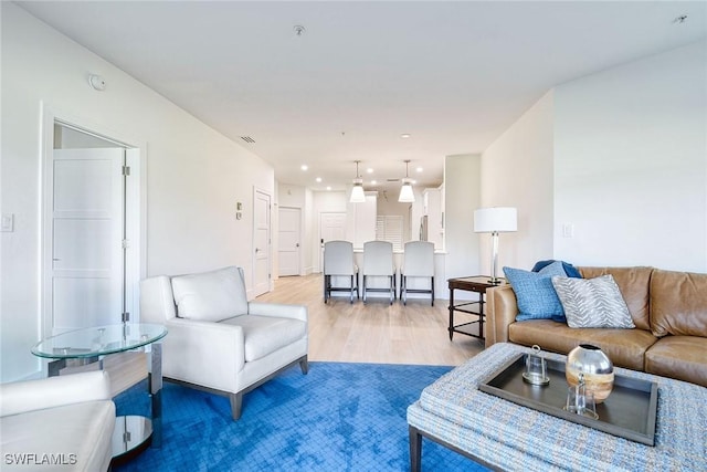 living room featuring light wood finished floors, visible vents, and recessed lighting