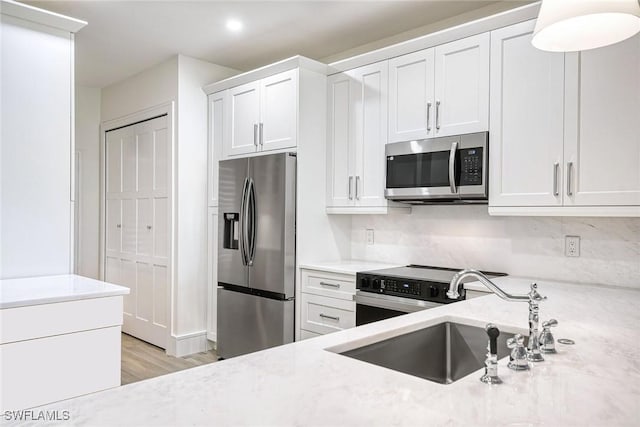 kitchen featuring appliances with stainless steel finishes, a sink, and white cabinets