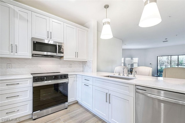 kitchen featuring backsplash, light wood-style flooring, appliances with stainless steel finishes, white cabinetry, and a sink