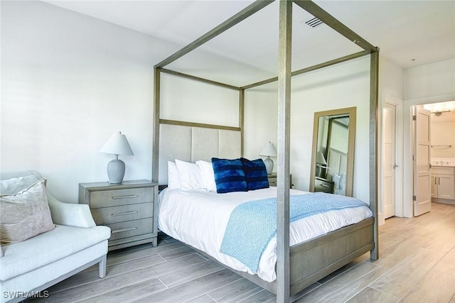 bedroom with light wood-type flooring, connected bathroom, and visible vents