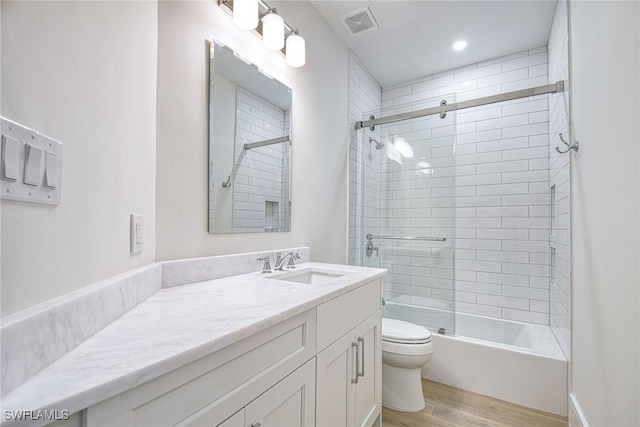 bathroom with bathing tub / shower combination, visible vents, toilet, vanity, and wood finished floors