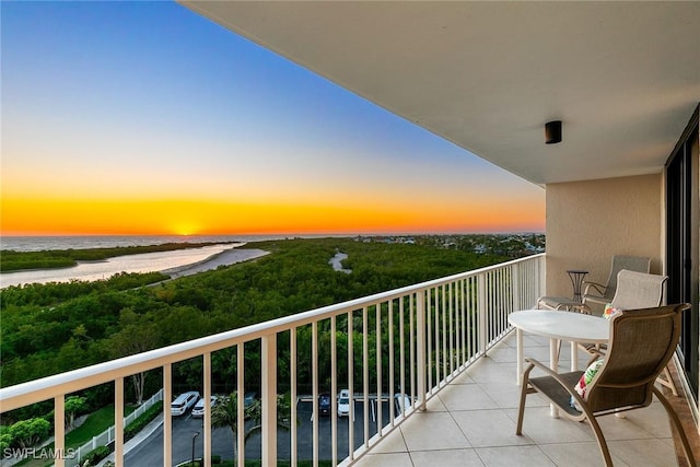 balcony at dusk featuring a water view