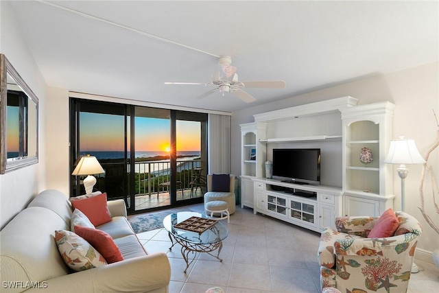 living room with a wall of windows, a ceiling fan, and light tile patterned flooring