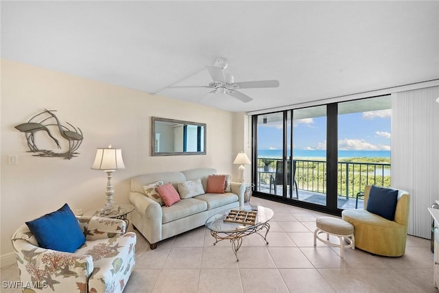 living room featuring a wall of windows, a ceiling fan, a water view, and light tile patterned floors