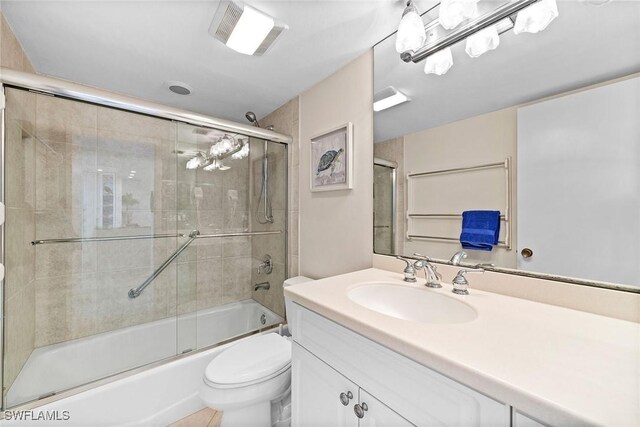 full bath featuring visible vents, vanity, toilet, and bath / shower combo with glass door