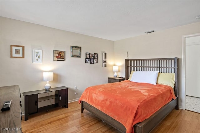 bedroom featuring light wood finished floors, baseboards, and visible vents