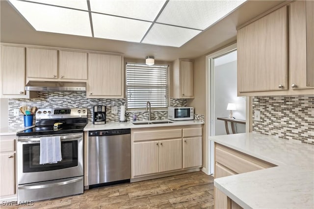 kitchen featuring light brown cabinets, stainless steel appliances, a sink, and under cabinet range hood