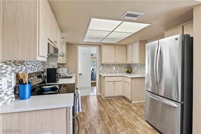 kitchen with stainless steel appliances, visible vents, light wood-style flooring, and light brown cabinetry