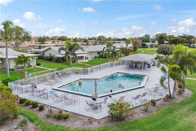 community pool featuring a yard, a residential view, fence, and a patio