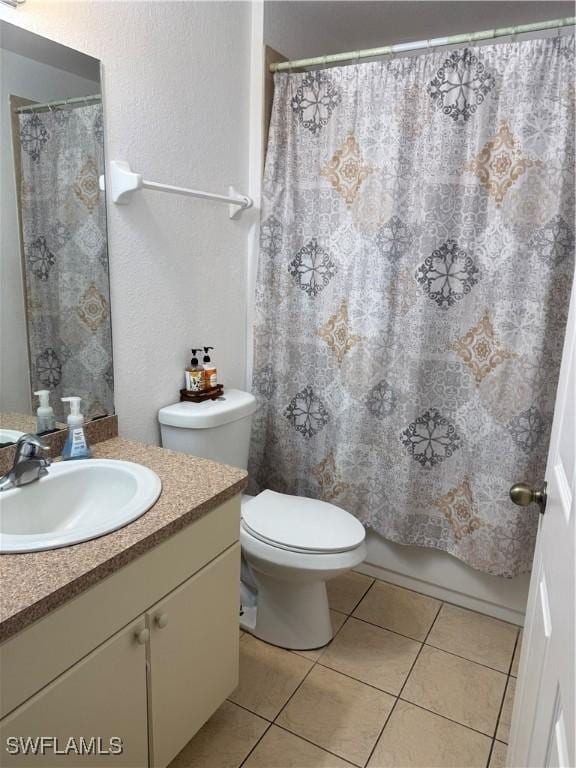 bathroom with toilet, tile patterned flooring, vanity, and shower / tub combo with curtain