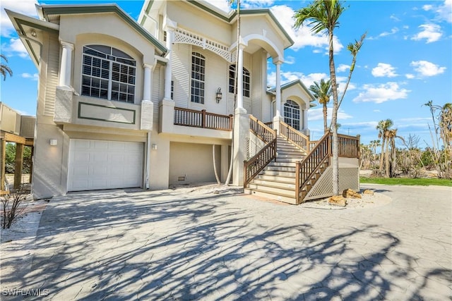 view of front of house featuring decorative driveway, stucco siding, an attached garage, and stairs