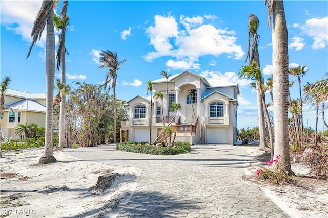 view of front of property with decorative driveway, stairway, an attached garage, and stucco siding