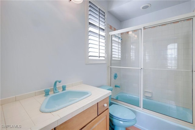 full bathroom featuring combined bath / shower with glass door, vanity, and toilet