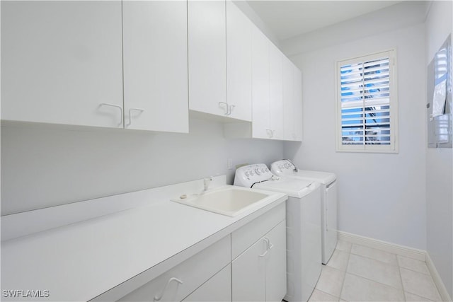 clothes washing area with cabinet space, light tile patterned floors, baseboards, washer and clothes dryer, and a sink