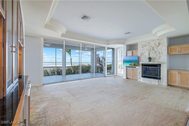 unfurnished living room with a premium fireplace, a raised ceiling, and visible vents