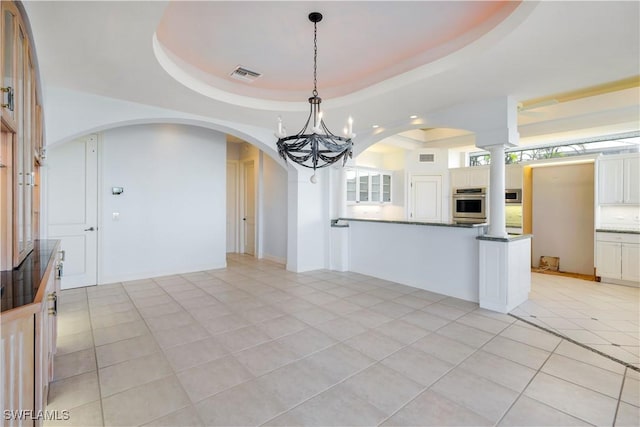 kitchen featuring light tile patterned floors, visible vents, a raised ceiling, hanging light fixtures, and stainless steel appliances