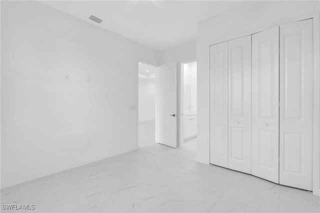 unfurnished bedroom with a closet, marble finish floor, and visible vents