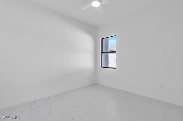 empty room featuring a ceiling fan, marble finish floor, and baseboards