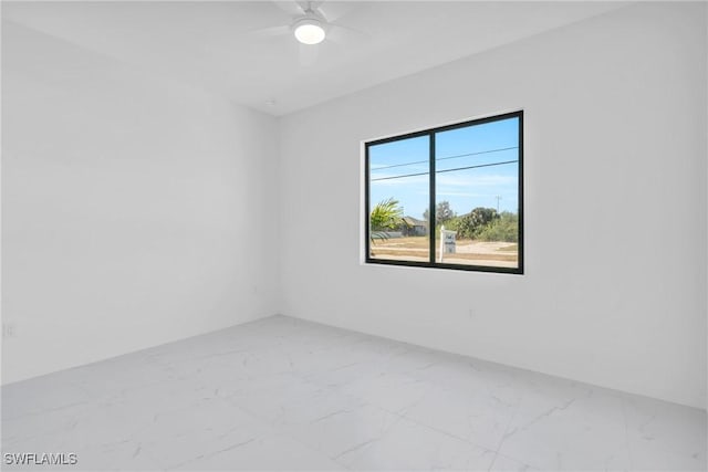 spare room featuring ceiling fan and marble finish floor