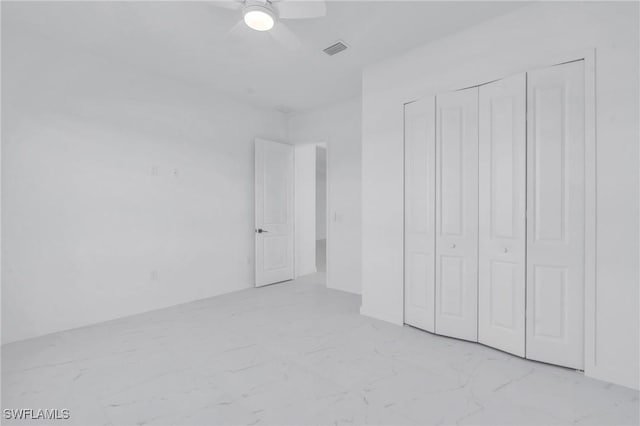 unfurnished bedroom featuring ceiling fan, marble finish floor, a closet, and visible vents