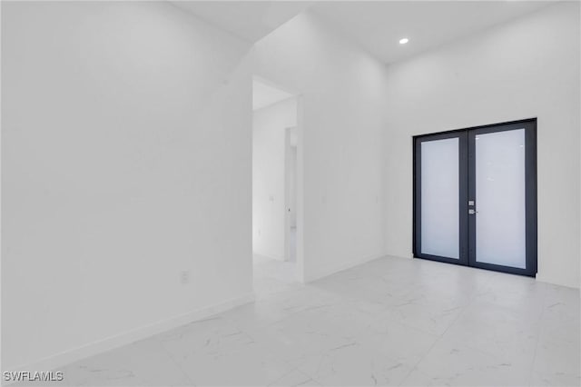 unfurnished room featuring marble finish floor, baseboards, and french doors