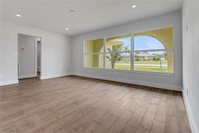 empty room with baseboards, wood finished floors, and recessed lighting