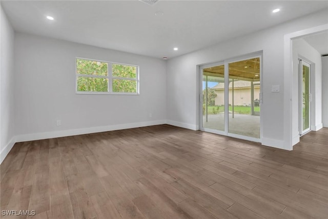 unfurnished room with recessed lighting, wood finished floors, and a healthy amount of sunlight