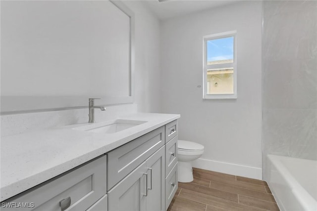 full bath featuring baseboards, toilet, a bathtub, vanity, and wood finish floors