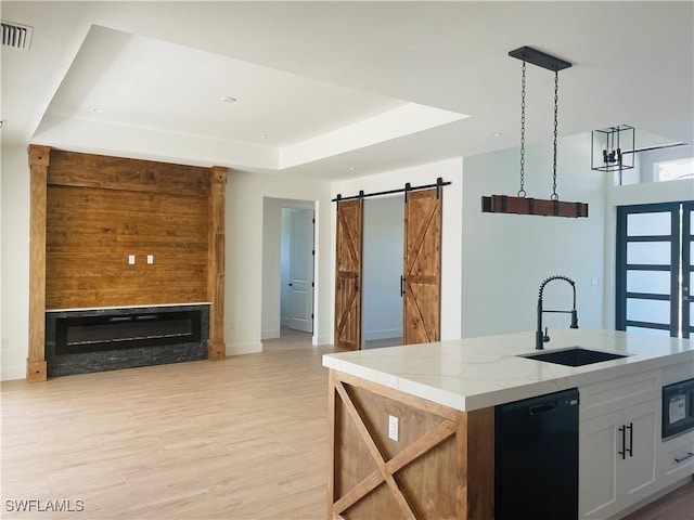 kitchen with visible vents, a sink, dishwasher, a barn door, and a raised ceiling