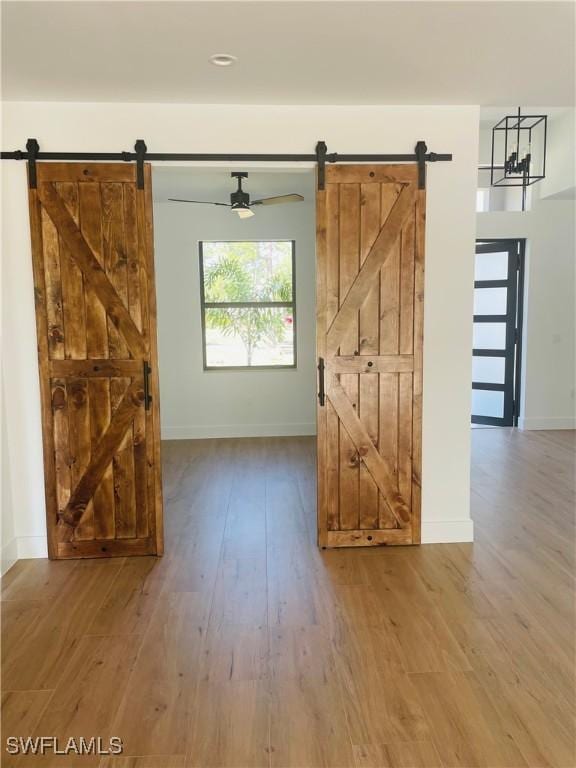 interior space with a barn door, baseboards, and wood finished floors