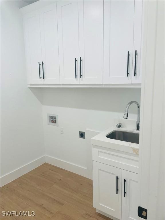 laundry area with washer hookup, light wood-style floors, cabinet space, hookup for an electric dryer, and a sink