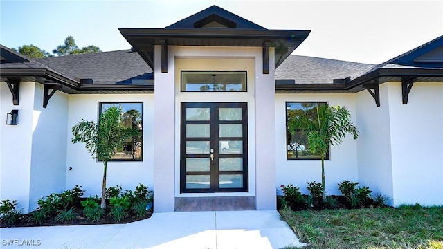 doorway to property with stucco siding and roof with shingles