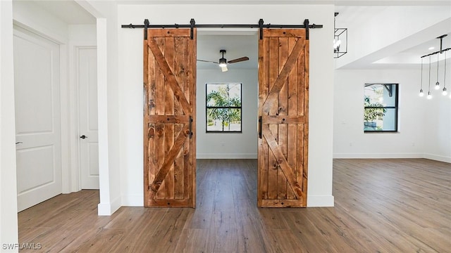 empty room with baseboards, a barn door, and wood finished floors