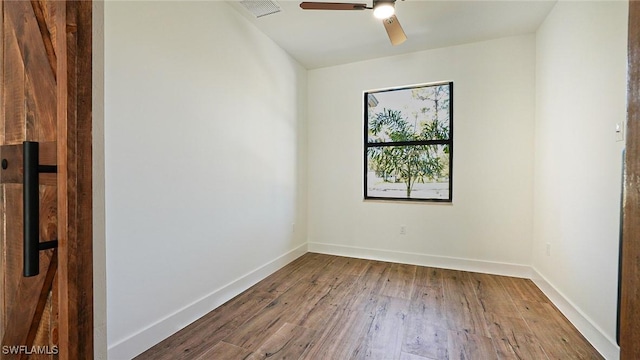 unfurnished room featuring a ceiling fan, wood finished floors, visible vents, and baseboards