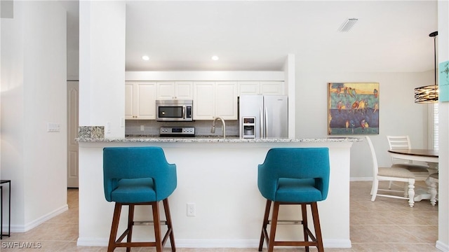 kitchen with appliances with stainless steel finishes, a breakfast bar, visible vents, and light tile patterned floors